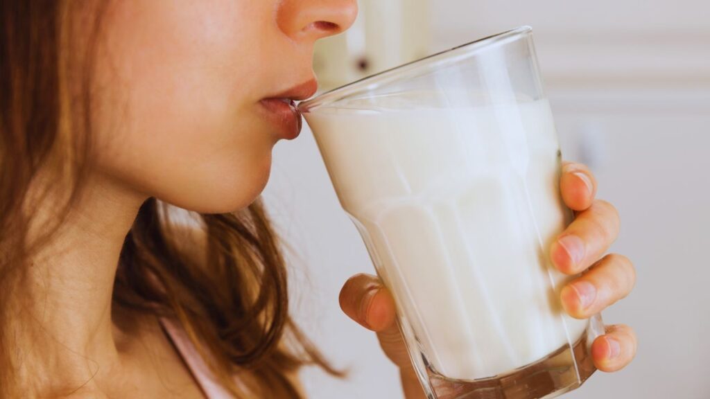 Giovane donna beve un bicchiere di latte